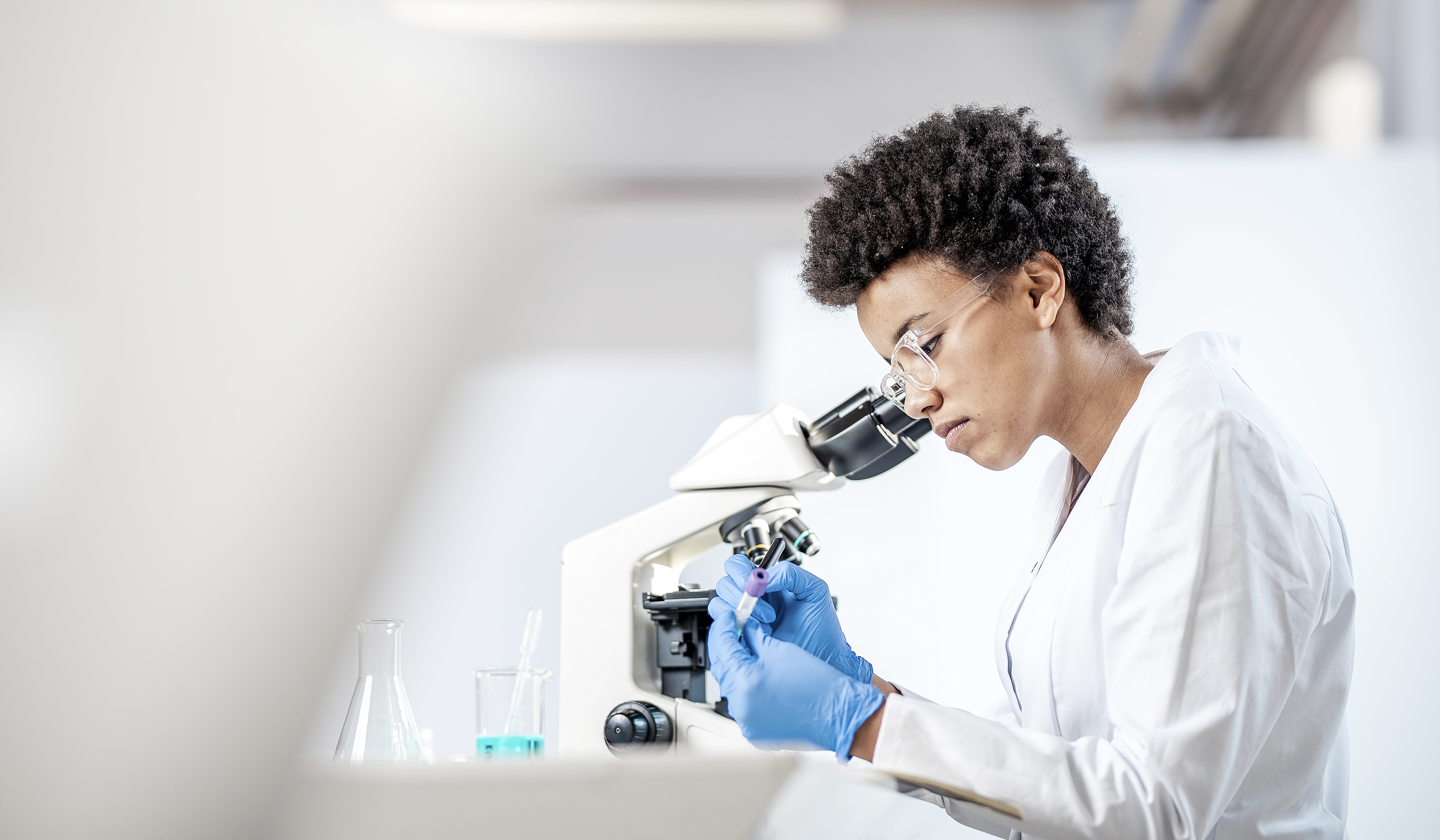 Female researcher in laboratory scrutinizing matter through a microscope