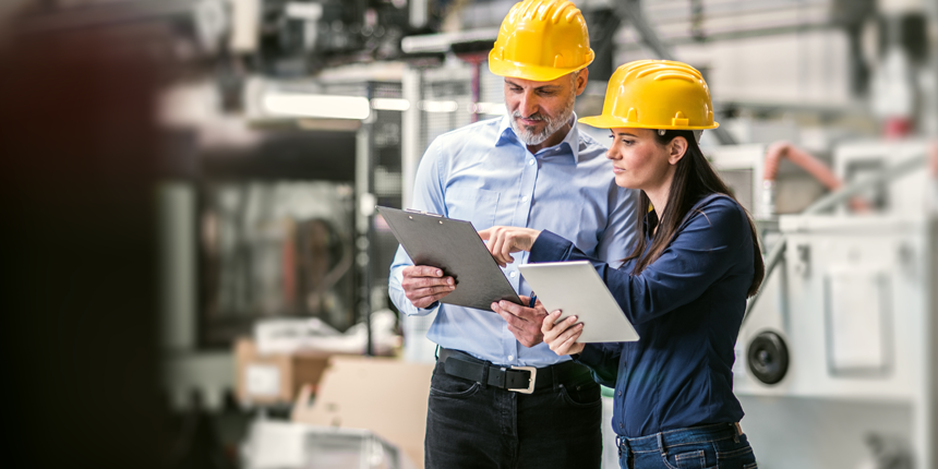 stock photo man and woman in a workplace with hardhats on