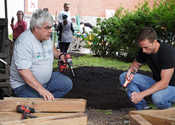 Engineers Canada’s Dan Villeneuve (left) and Adam Rodrigues (right) work together to build a wooden bench at an Ottawa Community Housing building on June 25, 2024.