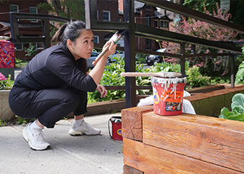 Engineers Canada’s Lisa Luo paints a railing at an Ottawa Community Housing building during Engineers Canada’s volunteer day on June 25, 2024