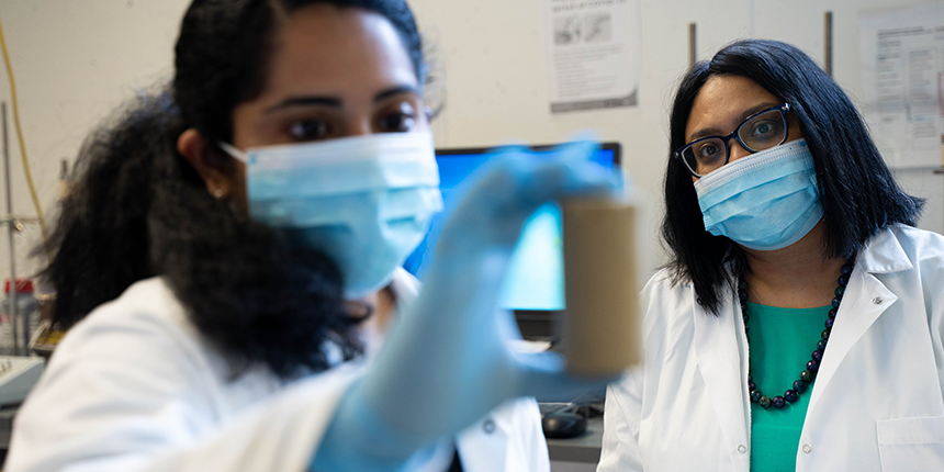 Deux scientifiques portant des masques et des blouses examinent un échantillon dans un laboratoire.