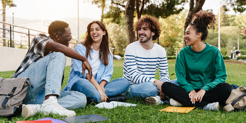 A group of four young people sitting on the grass