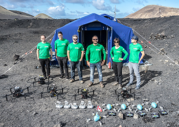 A group of individuals wearing green shirts stands together in front of a tent