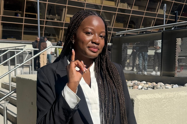 A professional woman with braids, dressed in a suit and tie.