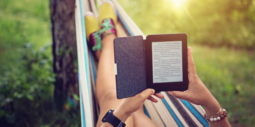 A woman, in a hammock, reading a book on her Kindle, focused and relaxed in a cozy outdoor setting.
