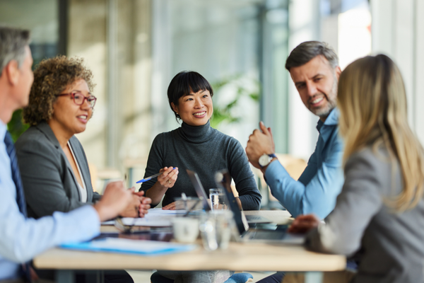 Business professionals engaged in a meeting around a conference table in a modern office setting.