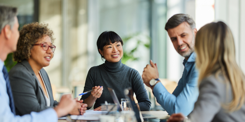 Business professionals engaged in a meeting around a conference table in a modern office setting.