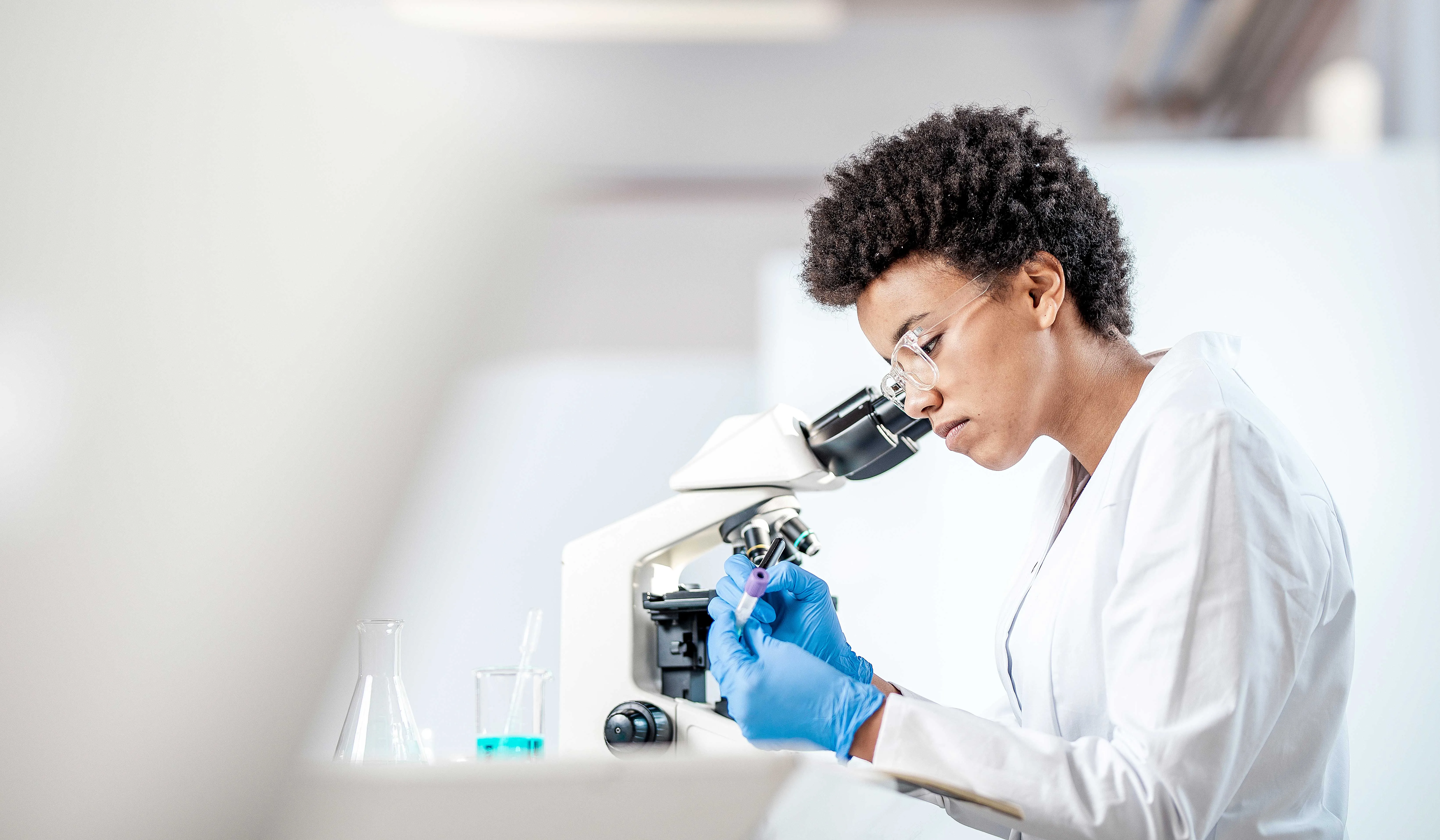 Female researcher in laboratory scrutinizing matter through a microscope