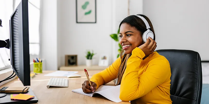The image shows a woman sitting at a desk wearing headphones. She is in an office setting.