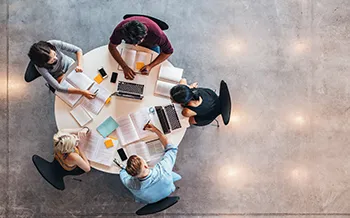 L'image est prise d'une perspective aérienne, montrant quatre personnes assises autour d'une table ronde.
