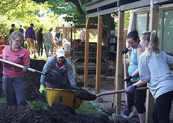 Engineers Canada’s Michaela Ryan, Joan Bard Miller, Julie Sendrowicz, and Alison Peverley work to grade and landscape the community yard at one of Ottawa Community Housing’s buildings on June 25, 2024.&nbsp;