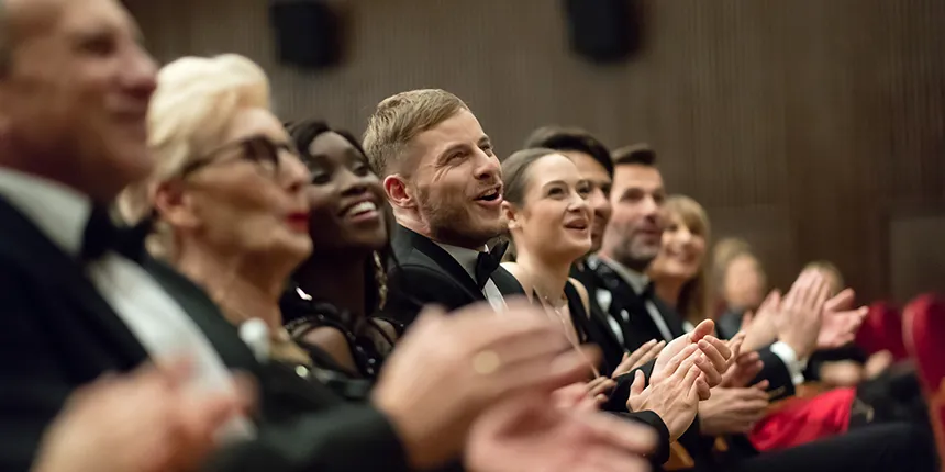 A gathering of people dressed in formal clothing, clapping their hands together